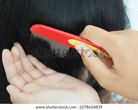 Mother checking child girl head for lice with a comb. Closeup photo, blurred.