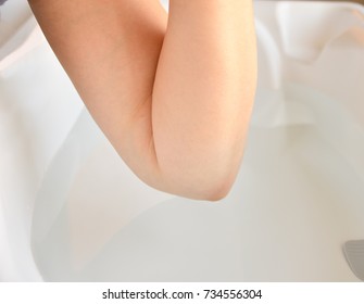 Mother Checking The Water Temperature Of A Child's Bathtub With The Elbow