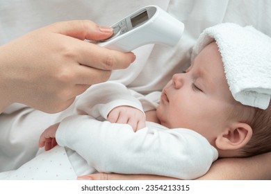 Mother checks newborn's temperature with thermometer. Concept of modern health care and safety