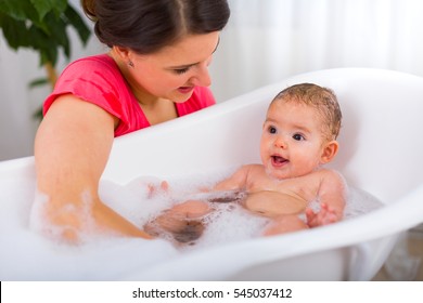 Mother And Child Bathing Together Playfully At Home.