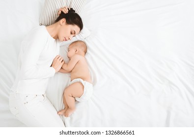 Mother And Child Connection. Young Woman Sleeping And Touching Her Baby's Hand, Top View With Free Space