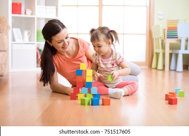 Mother And Child Daughter Building From Toy Blocks At Home. Family Concept.