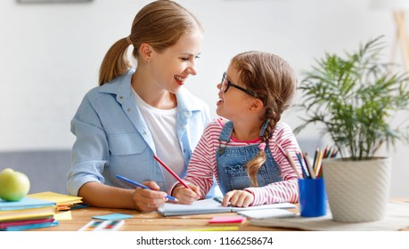 Mother And Child Daughter Doing Homework Writing And Reading At Home
