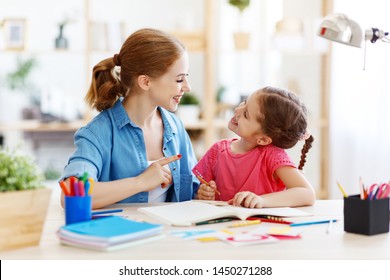 Mother And Child Daughter Doing Homework Writing And Reading At Home
