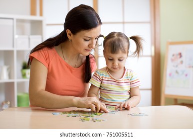 Mother And Child Daughter Playing At Home. Woman And Kid Assembling Jigsaw Puzzle