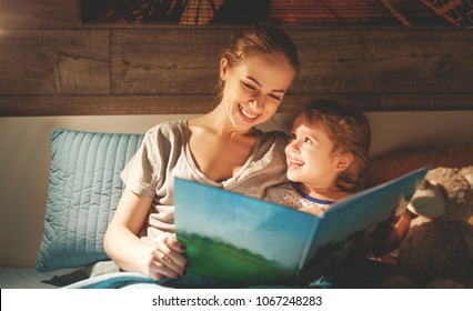 Mother And Child Daughter Reading Book In Bed Before Going To Sleep 
