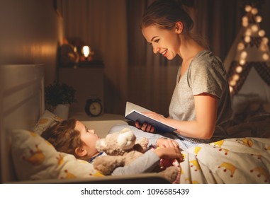 mother and child daughter reading book in bed before going to sleep 