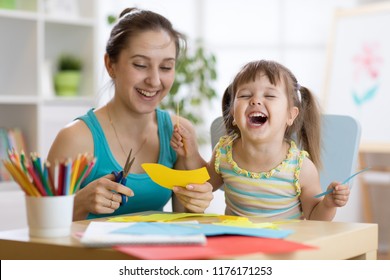 Mutter mit Kind-Tochter in gelbem Kleid, buntes Papier mit Schere schneiden