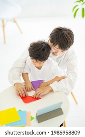 Mother And Child Doing Origami While Looking At A Tablet PC