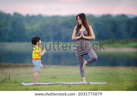 Mother and child doing yoga exercises for healthy and control mind in nature