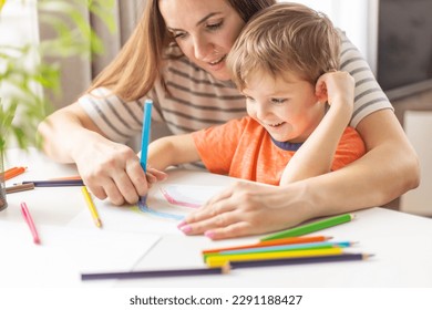 Mother and child drawing with pencils sitting at the desk at home - Powered by Shutterstock