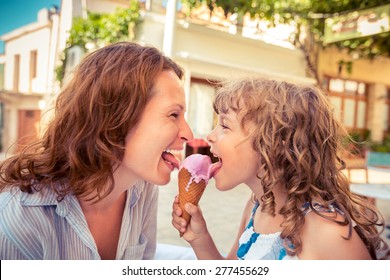 Mother and child eating ice cream in summer cafe outdoors
