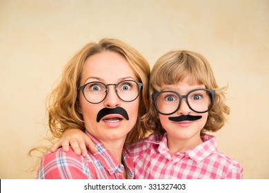 Mother and child with fake mustache. Happy family playing in home  - Powered by Shutterstock