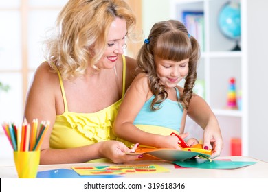 Mother with child girl drawing and cutting together