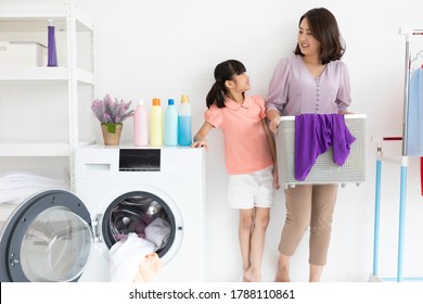 Mother And Child Girl Little Helper Are Having Fun And Smiling While Doing Laundry At Home