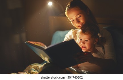 mother and child girl reading a book in bed before going to sleep - Shutterstock ID 504740302
