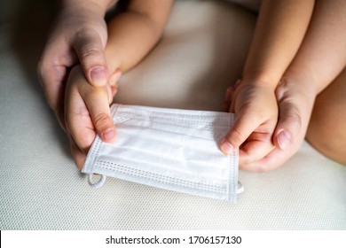 Mother And Child Hands Holding Protective Mask Together.  Family Taking Care Each Other Concept. Encourage People To Wear Face Mask In Public Area As A Precaution. Copy Space.