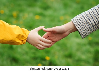 Mother And Child Hands Reaching To Each Other. Support, Help And Trust. Parent Holds The Hand Of A Child On A Walk. Kid And Mother Hands On Nature Background. Love, Relationship And Teamwork In Family