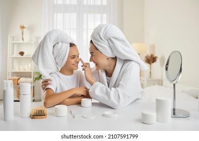 Mother and child having fun during skin care routine. Happy beautiful mommy and pretty little daughter sitting at beauty table, enjoying self care, applying face cream and having good time together
