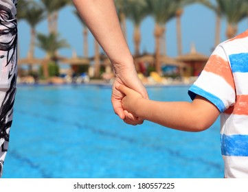 Mother And Child Holding Hands On Vacation Looking At Swimming Pool Concept For Family Vacations, Child Safety And Single Parent Holiday