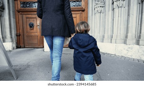 Mother and child holding hands walking into Religious temple reaching for doorknob and opening to wooden traditional door - Powered by Shutterstock