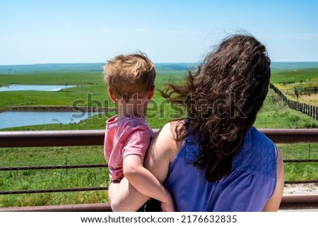 Mother and child looking over a fence at the Feed Yard Scenic Overlook outside of Dodge City, Kansas.