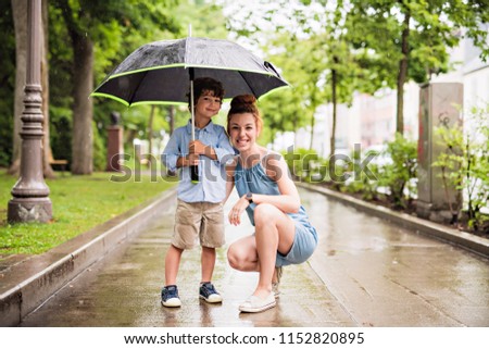 mother and child on a rainy day in a park with umbrella