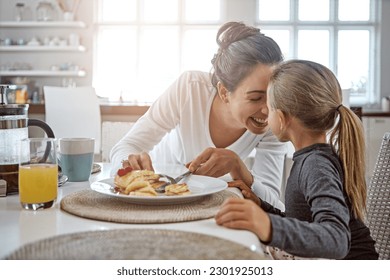 Mother, child and pancakes for breakfast in a family home with love, care and happiness at a table. A happy woman and girl kid eating food in plate together in morning for health and wellness - Powered by Shutterstock