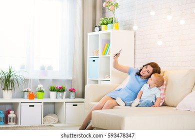 Mother with child photoshooting on smartphone selfie in the home room - Powered by Shutterstock