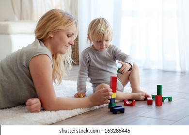 Mother With A Child Playing With Wooden Blocks At Home