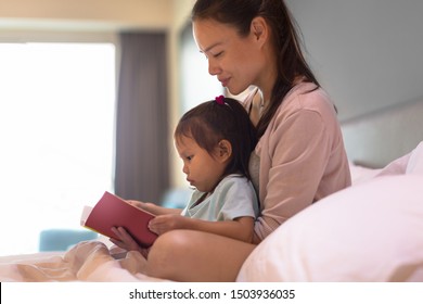 Mother and child reading a book in bed. - Powered by Shutterstock