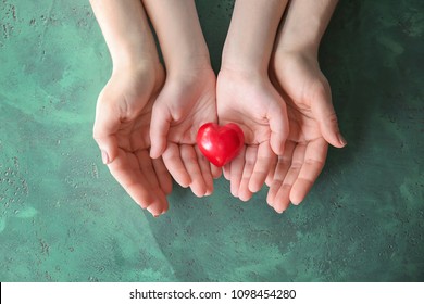 Mother and child with red heart on color background. Health care concept