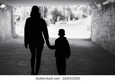 Mother child silhouette walking in a urban street setting 