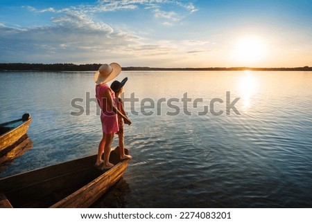 Mother and child at sunset in boat on seascape background.