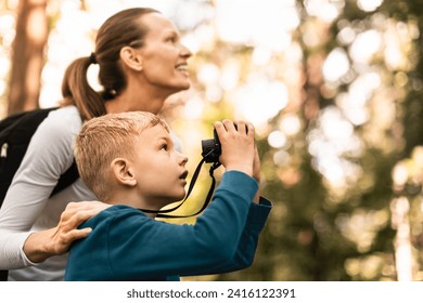 Mother child together hiking in the forest looking through binoculars bird watching exploring learning about nature, family adventure  - Powered by Shutterstock