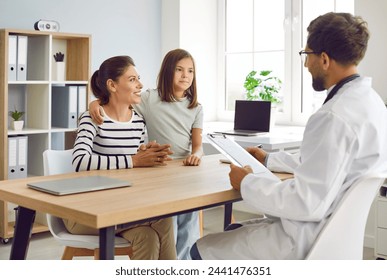 Mother and child visit family doctor at modern clinic. Happy, smiling mom and daughter sitting at table together with man pediatrician and talking about medical checkup results. Healthcare concept  - Powered by Shutterstock