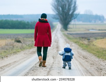 Mother With Child Walking By Rural Sandy Road