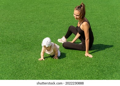 mother and child are walking on the green lawn, the child is crawling on its own