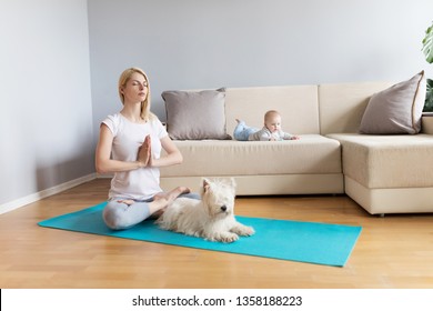 Mother And Child With White Dog In A Bright Room With Grey Walls And Wooden Floor On Blue Mat Exercising Yoga Calm Fitness White Sofa Counch In Home 