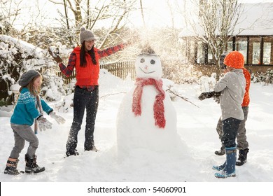 Mother And Children Building Snowman In Garden