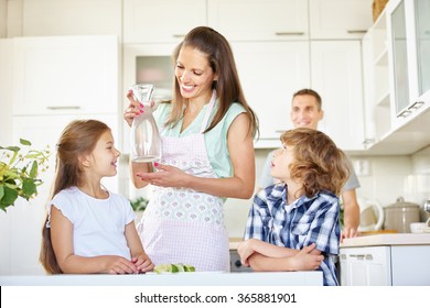 Mother and children with carafe water in the kitchen