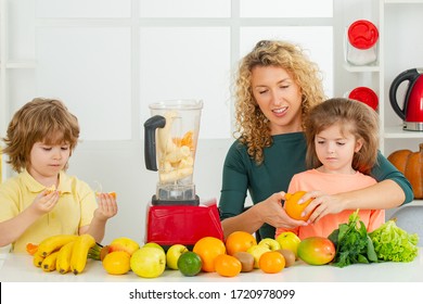 Mother With Children Making Smoothie In A White Kitchen. Family Mother And Child Daughter And Son Blended Smoothie With Healthy Fruits Ingredients. Detox Smoothie And Healthy Food