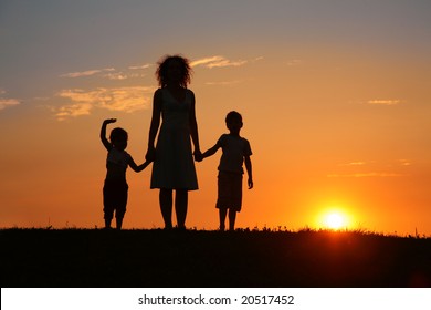 Mother And Children On Sunset Silhouette