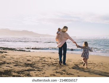 Mother with children playing and having fun together on beach ocean. Happy family outdoors. Mom and kids at summer on nature. Positive human emotions and feelings. Family holiday on sea coast.
