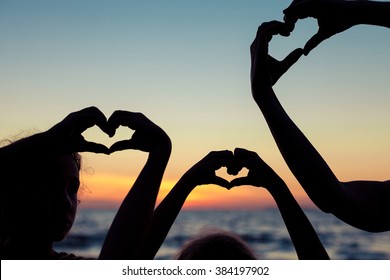 Mother and children playing on the beach at the sunset time. Concept of happy friendly family. - Powered by Shutterstock