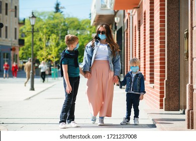 Mother And Children In Safety Masks Walking City Street. Family Wearing Face Masks Outdoors. Coronavirus Outbreak. Medical Masks To Prevention Coronavirus. New Real Life 2020. Lifestyle, Travel.