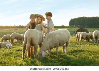 Mother and children stroking sheep on pasture. Farm animals - Powered by Shutterstock