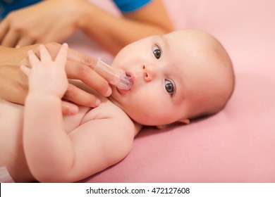 Mother Cleaning Baby`s Mouth With Special Fingertip Brush For Children