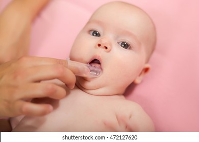 Mother Cleaning Baby`s Mouth With Special Fingertip Brush For Children