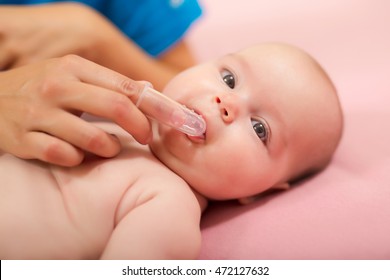 Mother Cleaning Baby`s Mouth With Special Fingertip Brush For Children